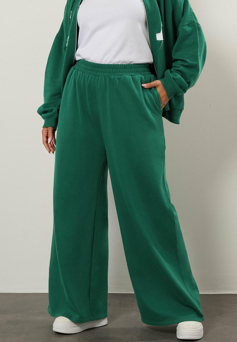 Gr üne, weit geschnittene Sweatpants aus weichem Stoff mit einem elastischen Bund, die seitliche Taschen und einen lockeren Sitz bieten.
