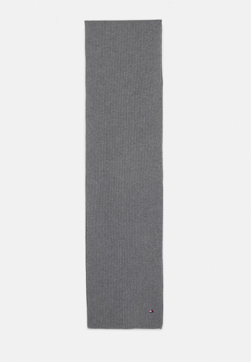 Longue écharpe grise en maille côtelée avec un petit logo rectangulaire rouge, blanc et bleu près d'un bord sur fond blanc.