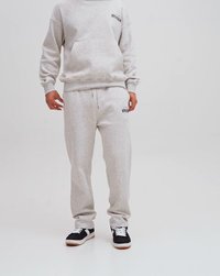Grå sweatshirt och matchande joggers, båda i mjukt tyg, med elastiska muddar och midja. Sneakers är svarta med vita accenter.