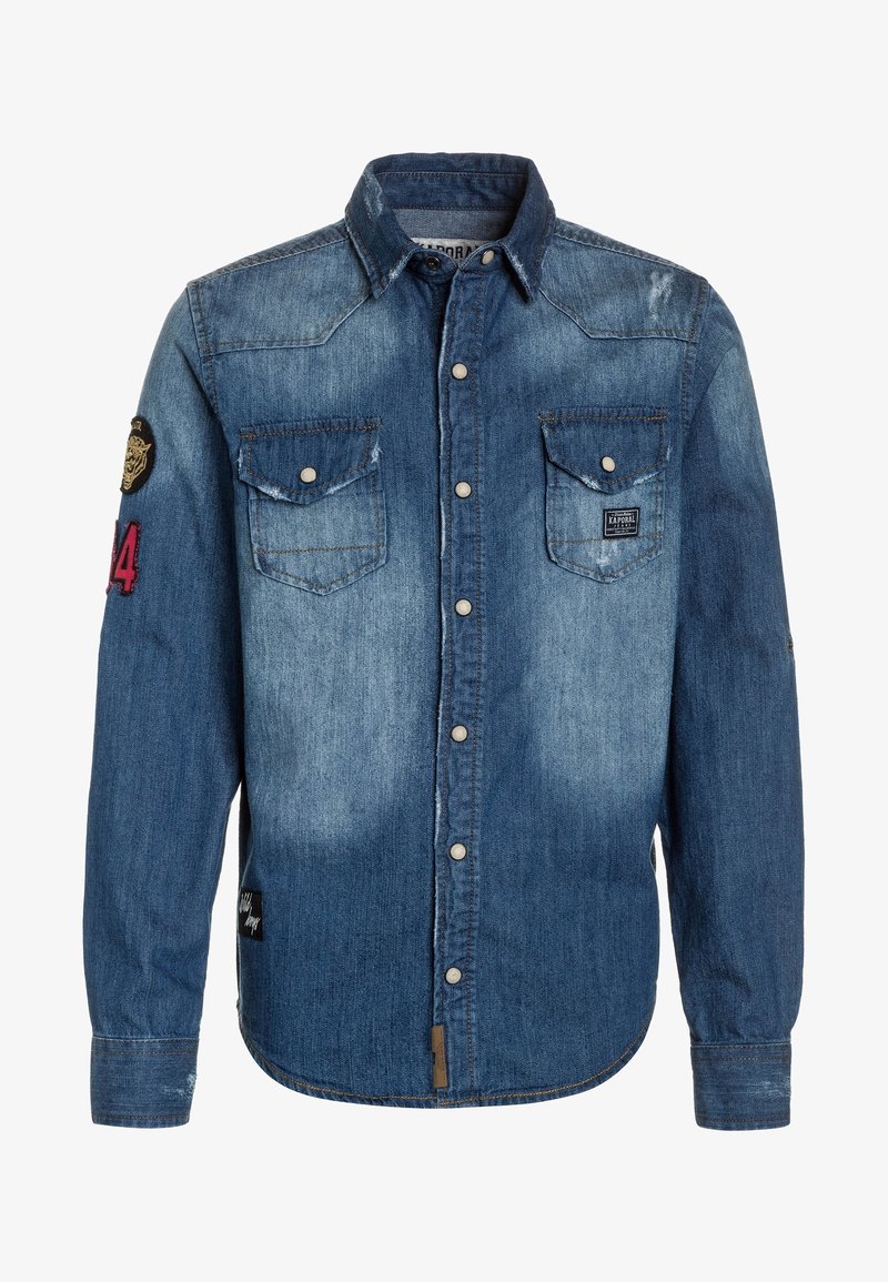 Camisa de mezclilla en diferentes tonos de azul, con cuello puntiagudo, dos bolsillos en el pecho y botones a presión. Incluye un parche en la manga.