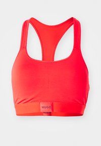 Reggiseno sportivo rosso con design a ferro di cavallo. Tessuto liscio, banda con logo nella parte inferiore e senza cuciture visibili per un look pulito.