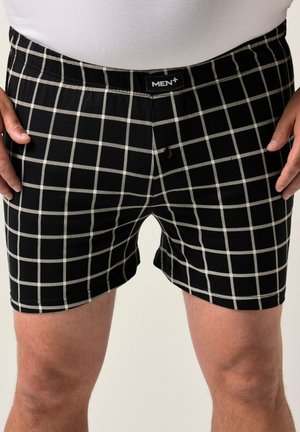 Calzoncillos negros con un patrón de cuadrícula blanca, con una cinturilla elástica etiquetada "HOMBRE+" y un cierre de botón sencillo en la parte frontal.