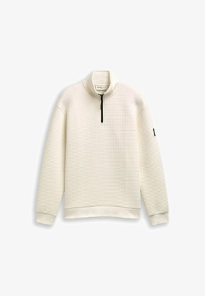 Pull à zip blanc en tissu texturé, avec un col montant et une fermeture éclair noire. Les poignets et l'ourlet côtelés accentuent le design.