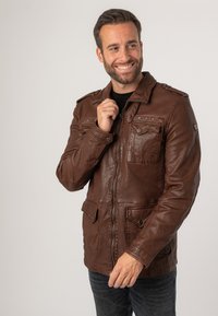 Braune Kunstlederjacke mit Reißverschluss und Druckknopfverschluss, ausgestattet mit vier vorderen Taschen und Schulterklappen. Glatte Textur, lässiges Design.