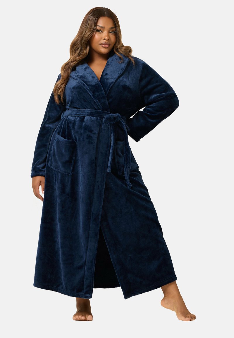 Tummansininen pitkä pörröinen kylpytakki, jossa on vyö, käännettävä kaulus ja kaksi etutaskua. Pehmeä rakenne ja täysipitkät hihat. Auki edestä.