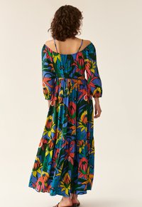 Maxikleid mit schulterfreiem Design, mit einem lebhaften Blumenmuster in Blau, Grün, Rot und Gelb. Leichtes Material, gestufter Saum.