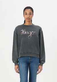 Gray sweatshirt with a round neckline, drop shoulders, and a loose fit. Features a script "Hugo" logo in pink on the front.