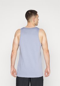 Herres singlet i lys lilla stoff, med rund halsutringning og avslappet passform, med en glatt tekstur. Vist fra baksiden.