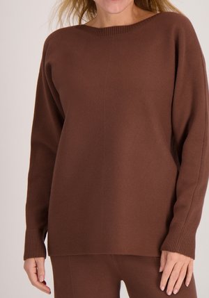 Bruine gebreide trui met brede halslijn, lange mouwen, geribbelde manchetten en een relaxte pasvorm. Zachte textuur en minimalistisch ontwerp.