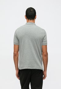 Γκ�ρι πόλο μπλούζα με γιακά και κοντά μανίκια, κατασκευασμένη από μαλακό ύφασμα, με ευθεία ραφή και χωρίς ορατά μοτίβα ή διακοσμήσεις.