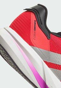 Red running shoe with mesh upper, Dynamic Fit collar, and silver accents. Features a white midsole with pink and gray sections and textured outsole.