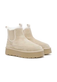 Stivaletti beige in suede con fodera morbida, pannelli laterali elasticizzati e una suola in gomma spessa e testurizzata. Linguette sul retro per una facile calzata.
