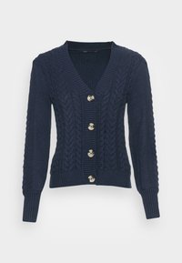 Marinblå stickad kofta med V-hals, knappstängning, texturerat kabelmönster samt ribbad manschetter och fåll. Fem stora knappar som detaljer.