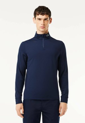 Polo a maniche lunghe blu navy con colletto a mezza zip, dotato di un piccolo logo sulla nuca, realizzato in tessuto morbido e leggero.