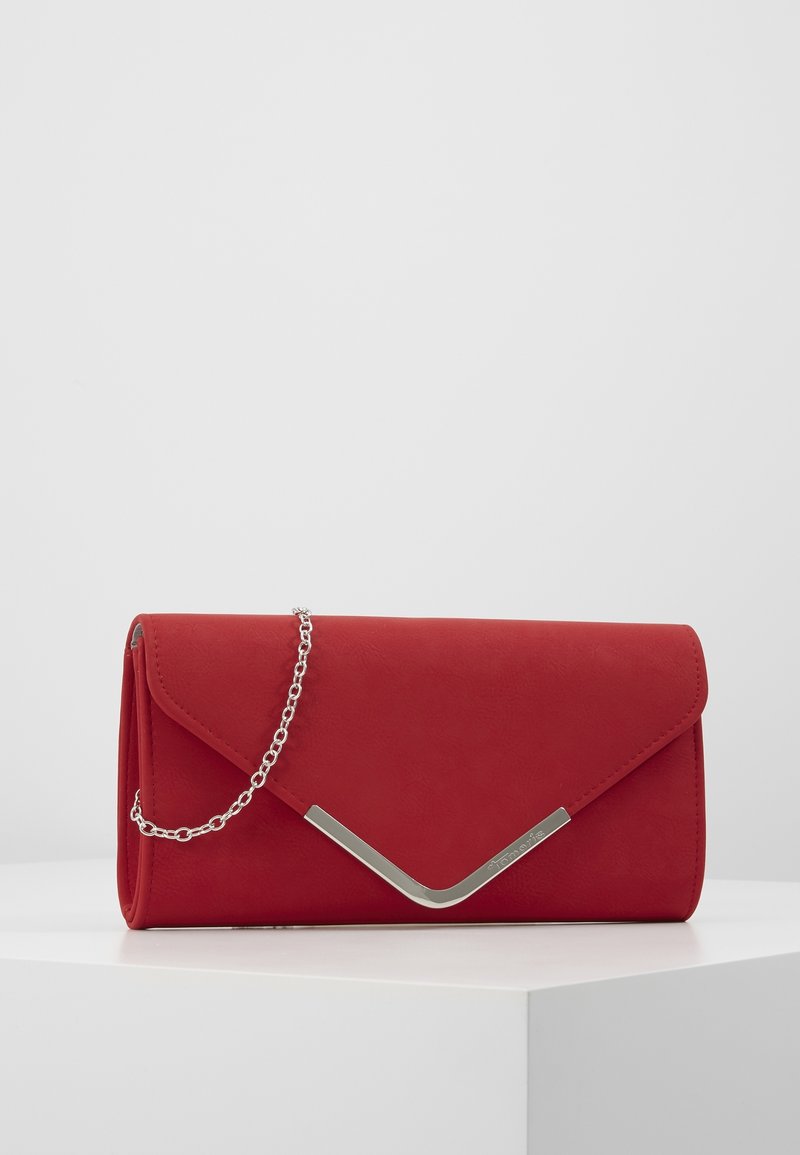 Pochette enveloppe rouge avec détail métallique en forme de V argenté et bandoulière chaîne, exposée sur un socle blanc sur un fond uni.