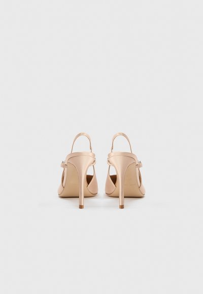 Beżowe satynowe buty na wysokim obcasie z odsłoniętym tyłem, posiadające cienki pasek i subtelny dekoracyjny element przy kostce.