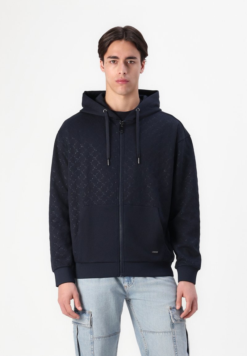 Felpa con zip di colore blu navy, caratterizzata da un motivo geometrico testurizzato nella parte superiore, con tasca a canguro e cappuccio regolabile con cordino.