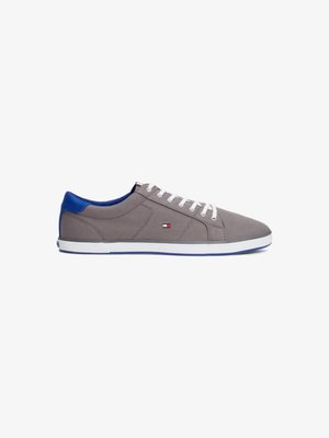 Sapatilha casual cinza e azul com atacadores brancos, perfil baixo, e um pequeno logótipo retangular vermelho, branco e azul de lado e no calcanhar.