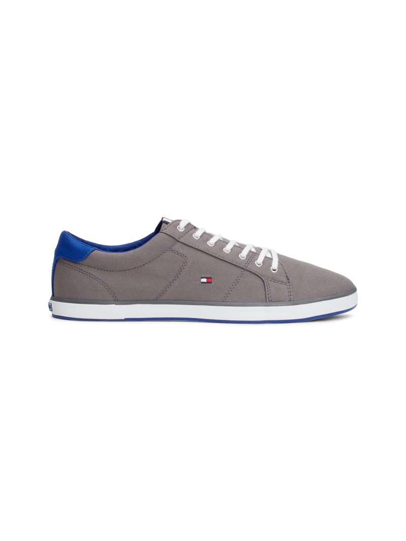 Sapatilha casual cinza e azul com atacadores brancos, perfil baixo, e um pequeno logótipo retangular vermelho, branco e azul de lado e no calcanhar.