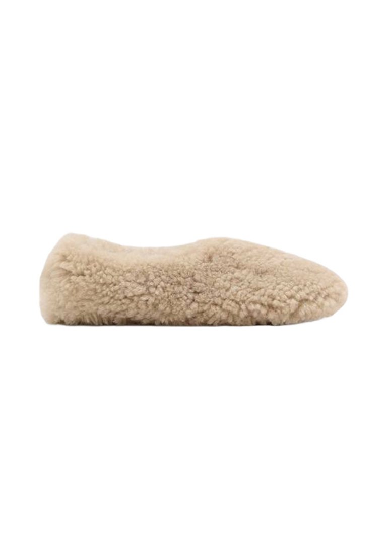 Beige pehmeä liukuva kenkä pyöreällä kärjellä ja matalalla profiililla, täysin peitetty pehmeällä, kiharaisella tekstuurikankaalla.