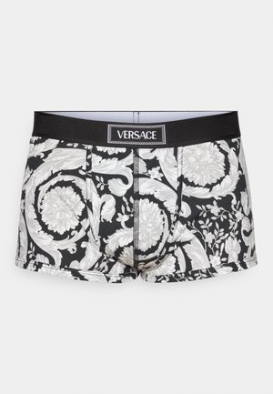 Fekete boxer alsónadrág fehér virágos és díszítő mintával, fekete elasztikus derékkal, amelyen a Versace logó látható.
