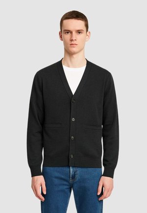 Cardigan nero con design a V, sei bottoni e due tasche frontali. Tessuto morbido e maniche lunghe, abbinato a jeans blu.