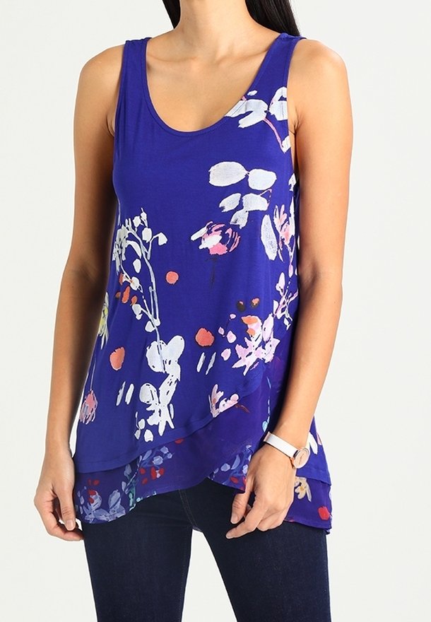 Bezrekawnik w kolorze purpurowym z kwiatowym wzorem w różu, bieli i zieleni, z warstwowym dołem i luźnym krojem. Nosi się go z ciemnymi dżinsami.
