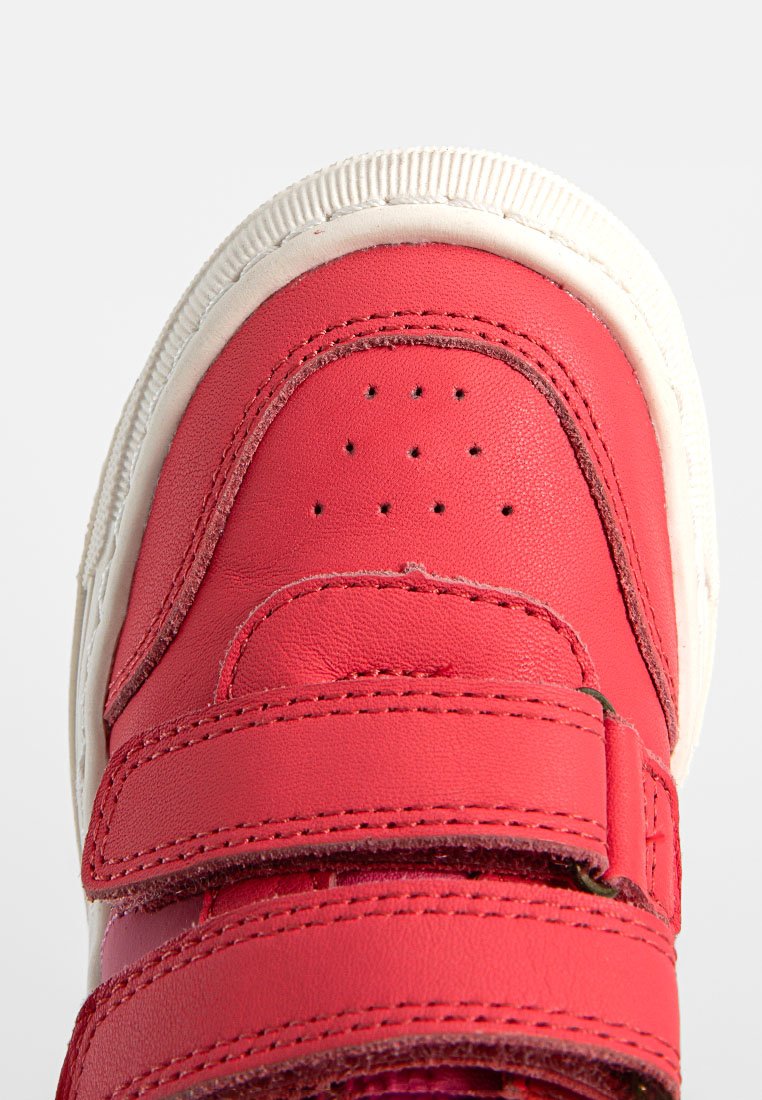 Rote Leder-Sneaker mit zwei Klettverschlüssen, runder Zehenpartie und strukturierten Oberflächen. Weiße Gummisohle mit leichtem Profil.