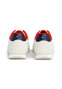 Białe i granatowe sneakersy z czerwonymi akcentami. Gładka skóra i zamsz, okrągły nosek, wyściełany kołnierz oraz detal z logo na pięcie.