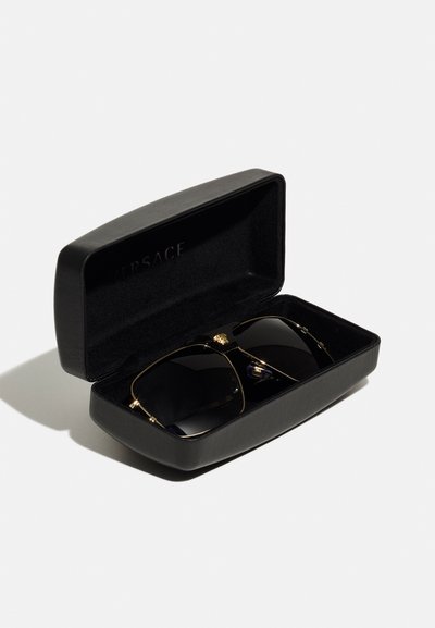 Gafas de sol negras en un estuche rectangular con acentos dorados. Las gafas cuentan con un marco negro brillante y lentes oscuros, con un logo en la varilla.