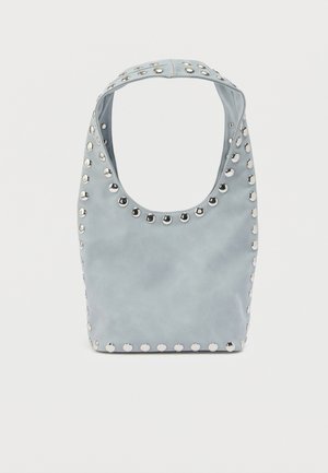 Lyseblå skuldertaske med sølvfarvede runde nitter, der markerer kanterne og håndtaget, mod en enkel hvid baggrund.