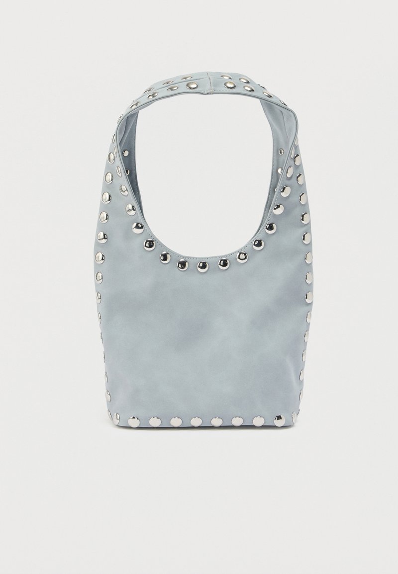 Sac à épaule bleu clair avec des clous ronds argentés soulignant les bords et la poignée, sur un fond blanc uni.