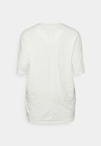 T-shirt branco de corte solto, com decote redondo, mangas curtas e detalhes de franzido nas laterais, em um tecido suave.