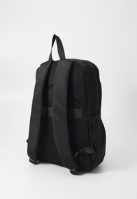 Sort rygsæk med polstret mesh-bag, brede justerbare stropper, firkantet form og lynlås. Glat stof og minimal hardware.