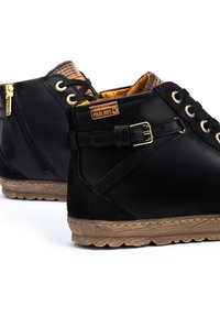Stivali alla caviglia in pelle nera con dettagli in metallo dorato, accenti beige e rivestimento fantasia. Presentano una zip laterale e un dettaglio con fibbia. Suola in gomma.