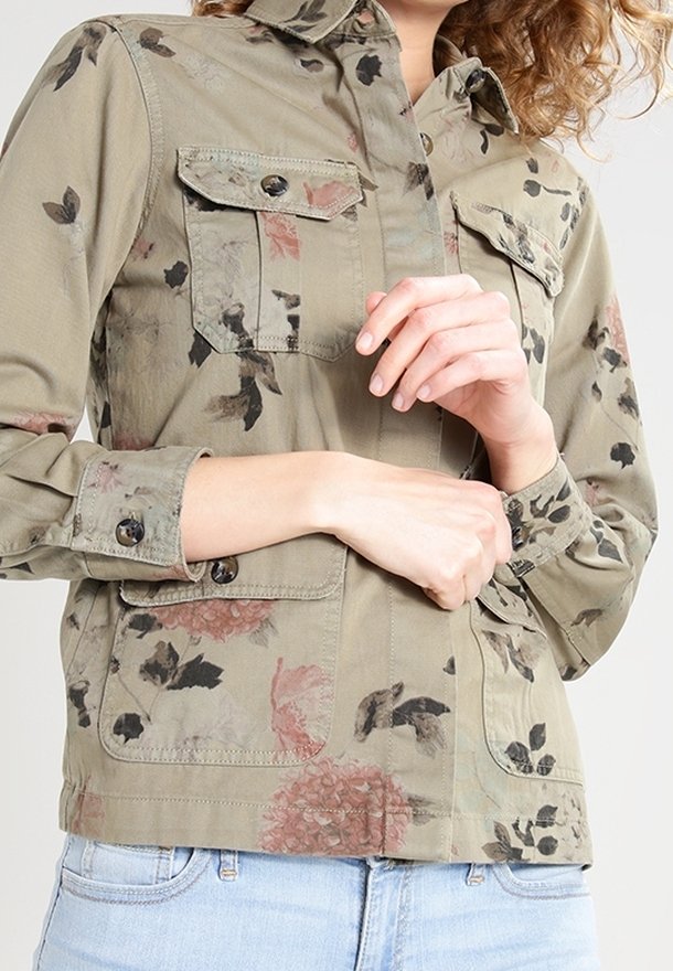 Blommönstrad khakifärgad jacka med knäppta bröstfickor och krage. Har en avslappnad passform och texturerad tyg.