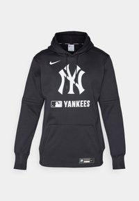 Juodas Nike džemperis su priekine kengūros kišene, turintis didelį baltą Yankees logotipą ir MLB prekės ženklą. Tekstūruota medžiaga su reguliuojama kapišonu.