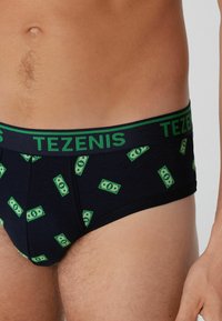 Culottes pour hommes en bleu marine avec un motif de billets. Dotées d'une ceinture élastique verte avec le logo "TEZENIS". Fabriquées en matière douce et extensible.