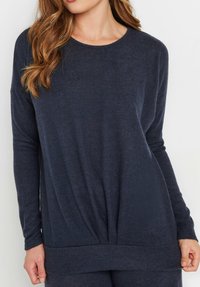 Maglietta a maniche lunghe blu navy in tessuto morbido, con scollatura rotonda e design drappeggiato, caratterizzata da un dettaglio arricciato sul fondo.