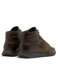 Brązowe skórzane i zamszowe buty typu mid-top mają gładkie wykończenie, kontrastujące tekstury, sznurowanie oraz grubą czarną gumową podeszwę.