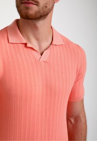 Polo tričko s krátkým rukávem, světle korálové barvy, ribbovaný povrch, plochý límeček, V-výstřih, přiléhavý střih, pletená tkanina.