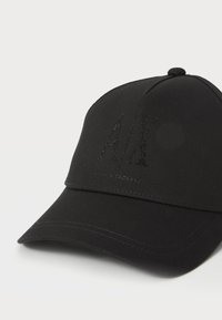 Casquette de baseball noire en tissu, ornée d'un logo AX texturé en strass noirs, avec une visière incurvée et des accents cousus.