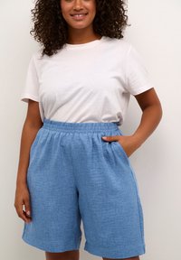 Light blue linen shorts with an elastic waistband, side pockets, and a relaxed fit, paired with a plain white t-shirt.