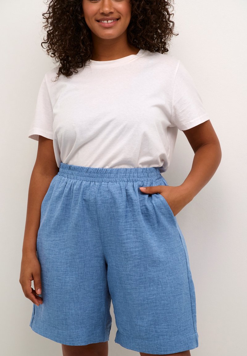 Light blue linen shorts with an elastic waistband, side pockets, and a relaxed fit, paired with a plain white t-shirt.