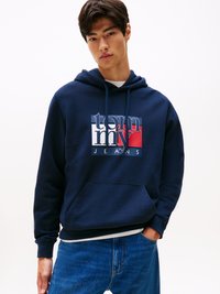 Felpa in cotone blu navy con logo frontale in bianco, rosso e blu navy. Progettata con cappuccio regolabile e tasca a marsupio. Polsini aderenti.