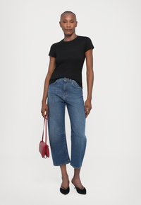 Black short-sleeved t-shirt, blue cropped jeans, red handbag, and black heeled mules. Simple design with classic fit and light texture.