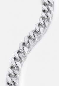 Bracelet en chaîne argentée avec des maillons lisses et entrelacés. Chaque maillon a une forme arrondie, créant une apparence continue et polie.