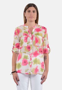 Camicia a stampa floreale in tessuto leggero con fiori di ibisco rosa e verdi, chiusura a bottoni sul davanti, colletto e maniche arrotolate.
