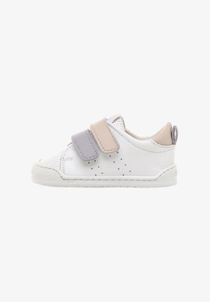 Zapatilla blanca para niños pequeños con puntera perforada, dos correas de velcro de colores pastel y una lengüeta beige en una suela plana.