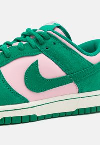 Grüner und pinkfarbener Sneaker aus Wildleder und Leder. Verfügt über einen auffälligen grünen Nike-Swoosh, eine strukturierte Oberfläche und eine weiße Sohle.